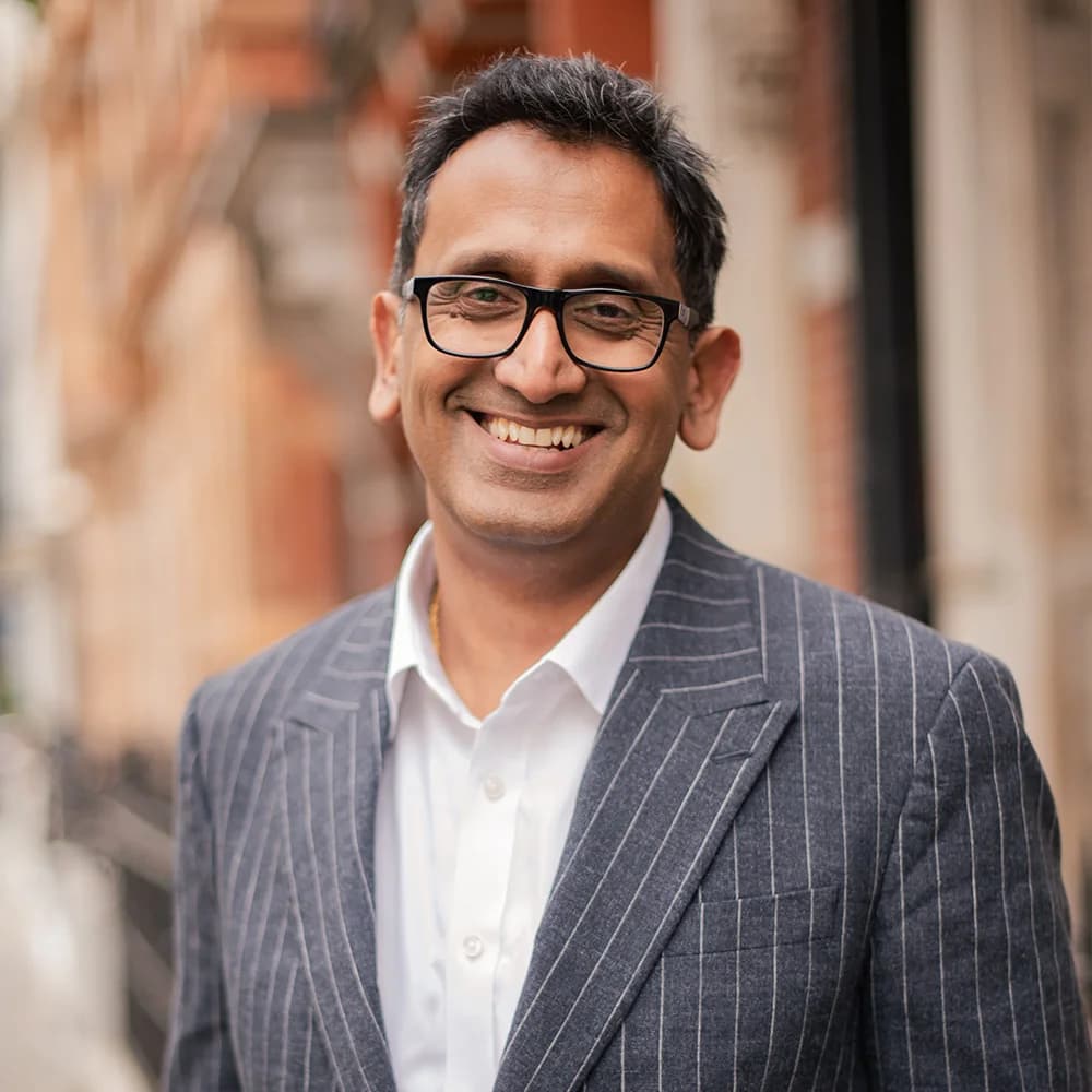 Professor Prasanna Sooriakumaran, smiling portrait in a pinstripe suit