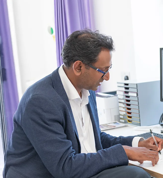 Professor Prasanna Sooriakumaran at his desk in consultation