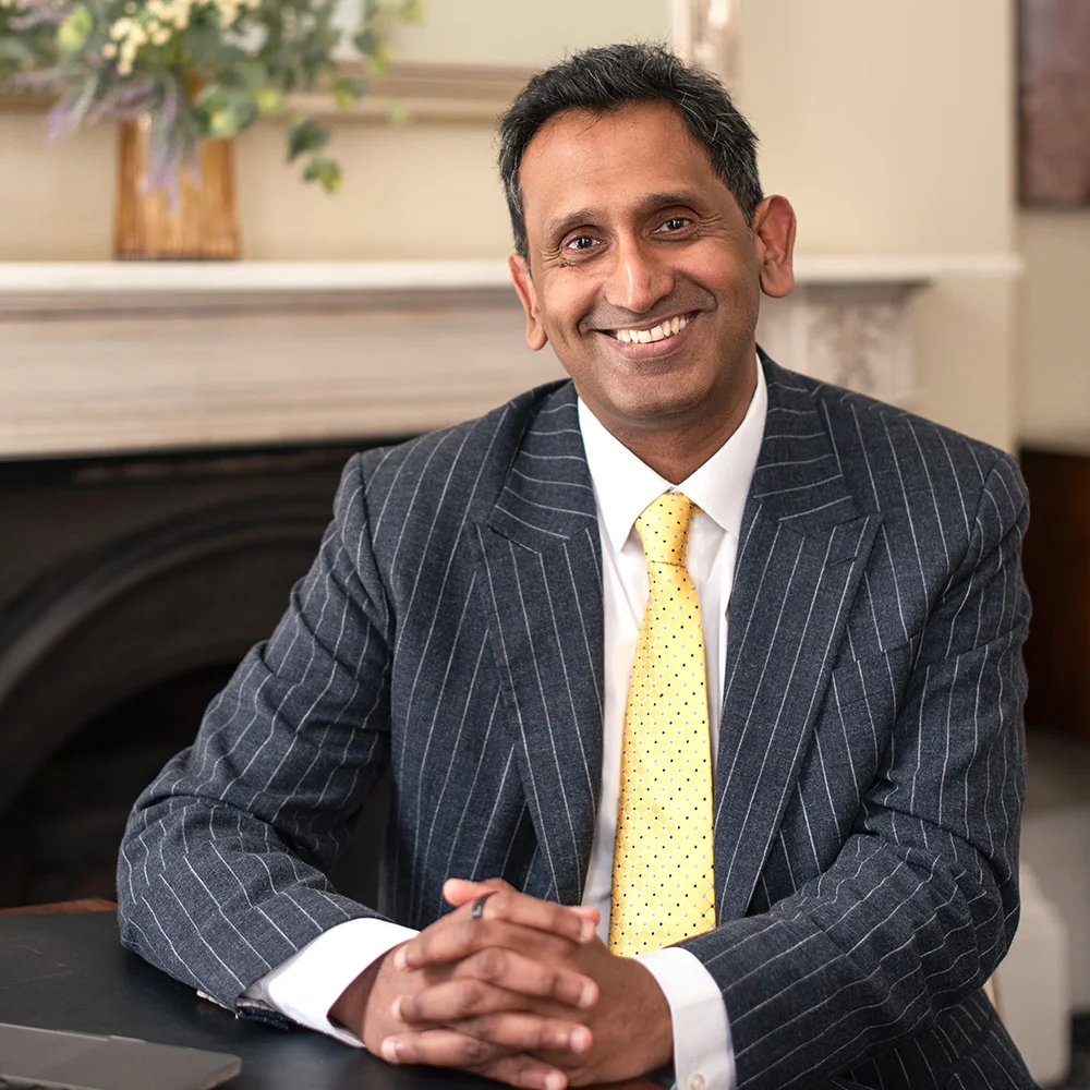 Professor Prasanna Sooriakumaran seated in a pinstripe suit and yellow tie