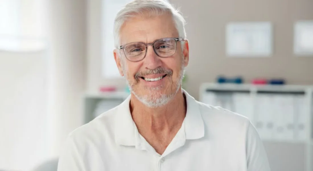 Smiling older man with glasses in a white polo shirt