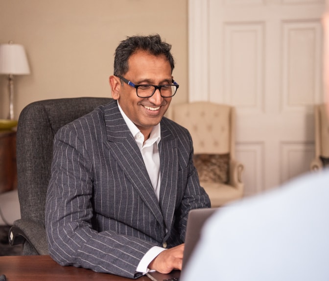 Professor Prasanna Sooriakumaran smiling at his desk during a consultation