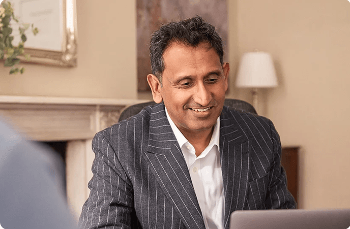 Professor Prasanna Sooriakumaran smiling at his desk