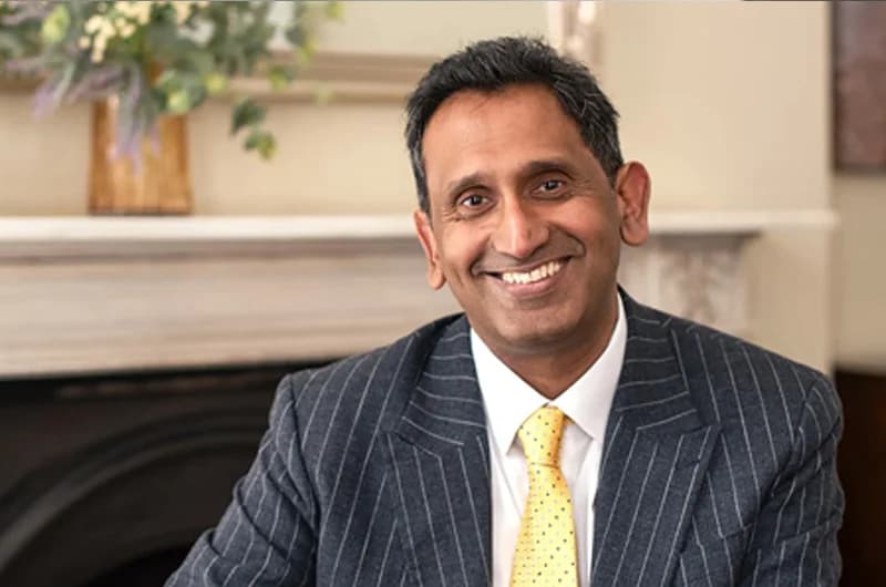 Professor Prasanna Sooriakumaran smiling in a pinstripe suit and yellow tie