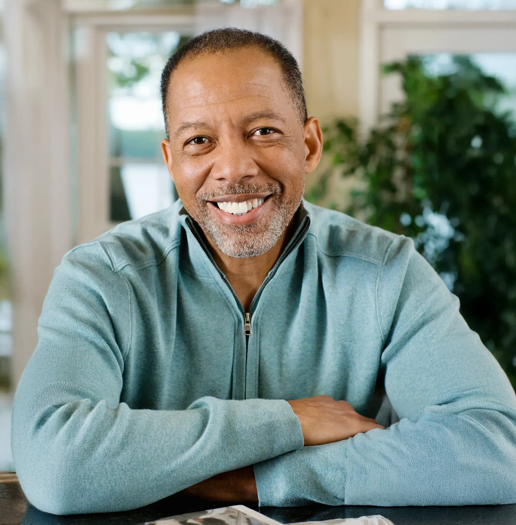 Smiling man in a green jumper seated at a table