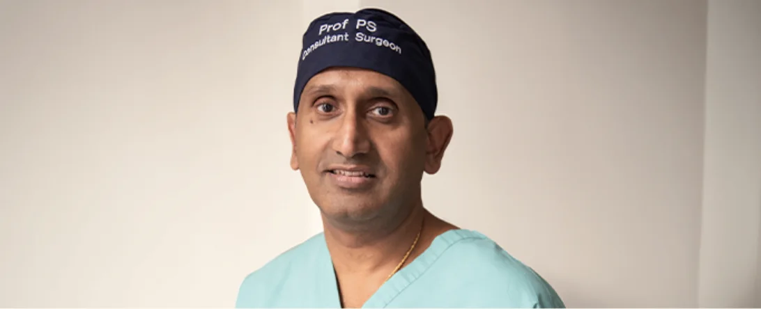 Professor Prasanna Sooriakumaran in a surgical cap and scrubs