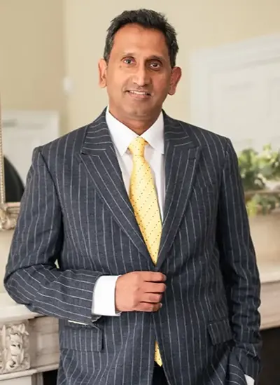 Professor Prasanna Sooriakumaran standing in a pinstripe suit and yellow tie